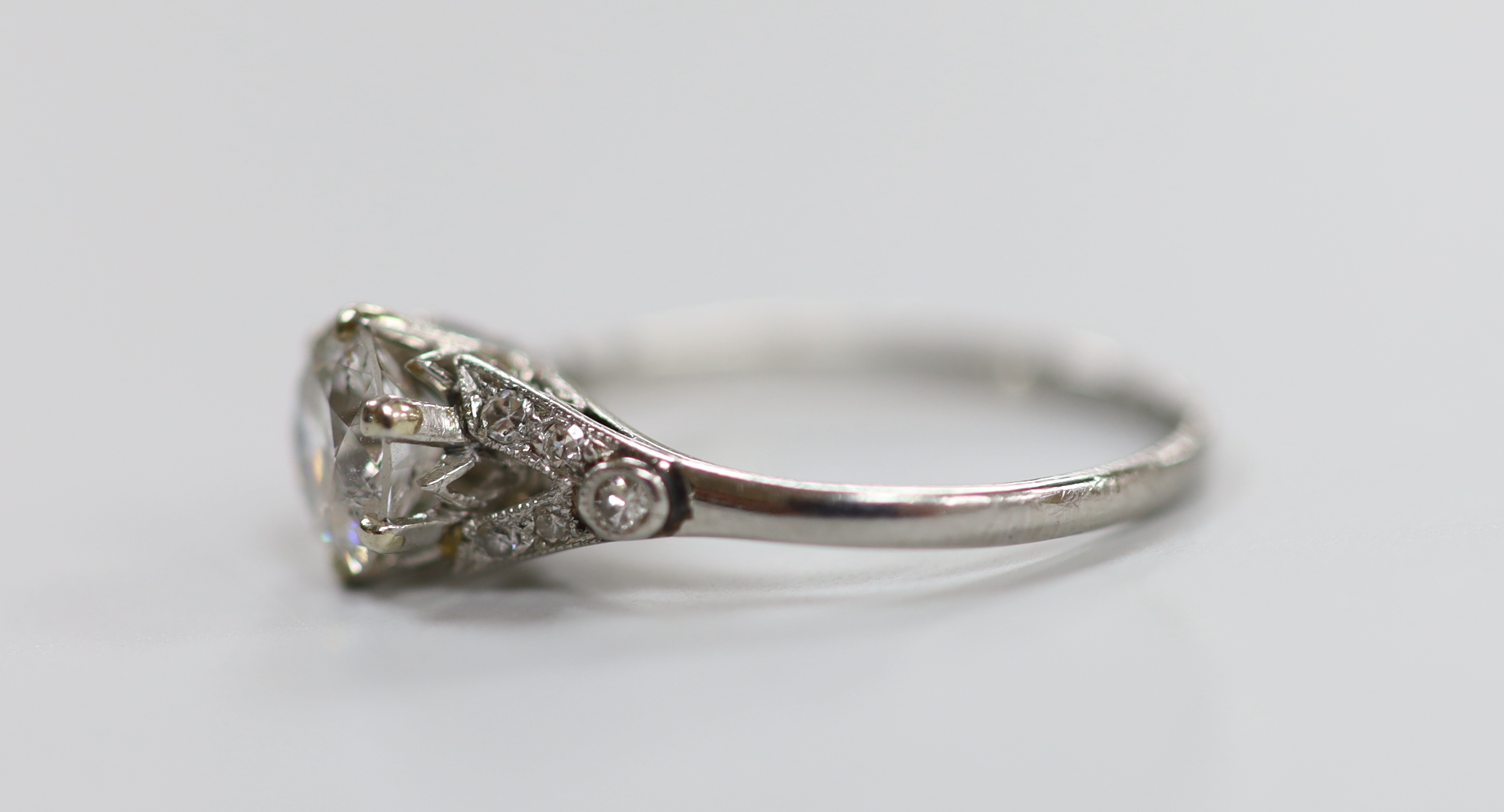 A white metal (stamped plat) and single stone diamond ring, with diamond chip set shoulders, size L/M, gross weight 2.4 grams